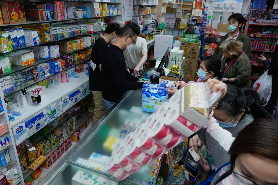 People purchase household supplies at a pharmacy as residents worry about a shortage of supplies in Hong Kong, Monday, Feb. 28, 2022. Hong Kong on Monday reported a record-high 34,466 infections, with health authorities saying that a lockdown has not been ruled out as fatalities continued to climb. (AP Photo/Vincent Yu)