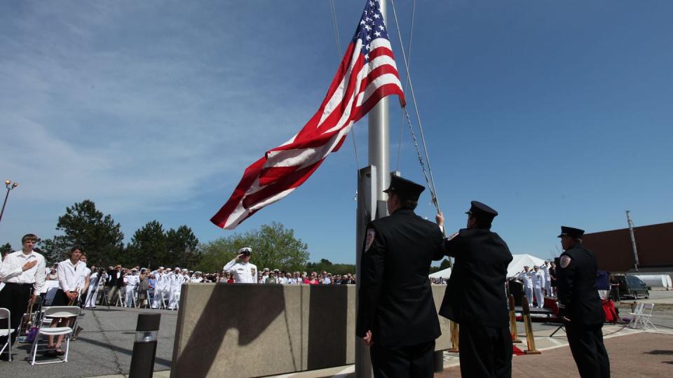 Firefighters lower the American flag during a 2011 ceremony marking the official closing of Naval Air Station Brunswick in Maine. A panel in charge of base closure and realignment activities voted to close the base in 2005. (Joel Page/AP)