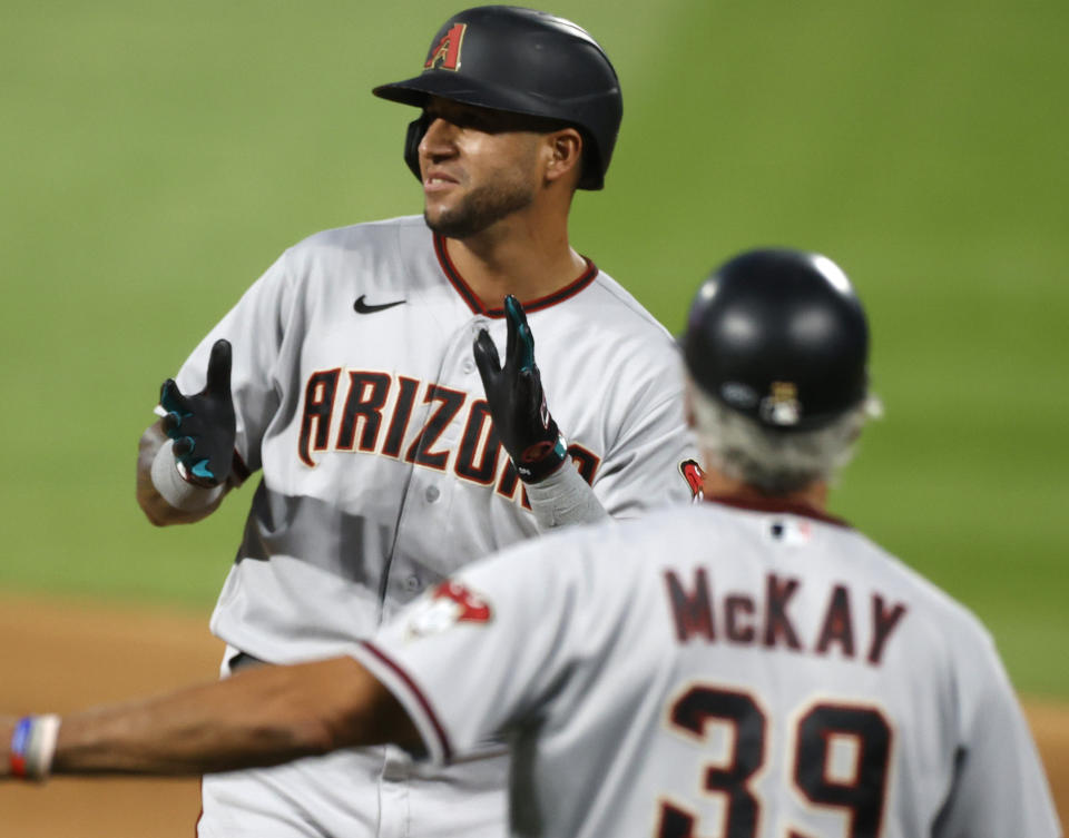 Arizona Diamondbacks' David Peralta, top, claps after hitting a single to drive in two runs off Colorado Rockies starting pitcher Jon Gray in the fourth inning of a baseball game Monday, Aug. 10, 2020, in Denver. (AP Photo/David Zalubowski)