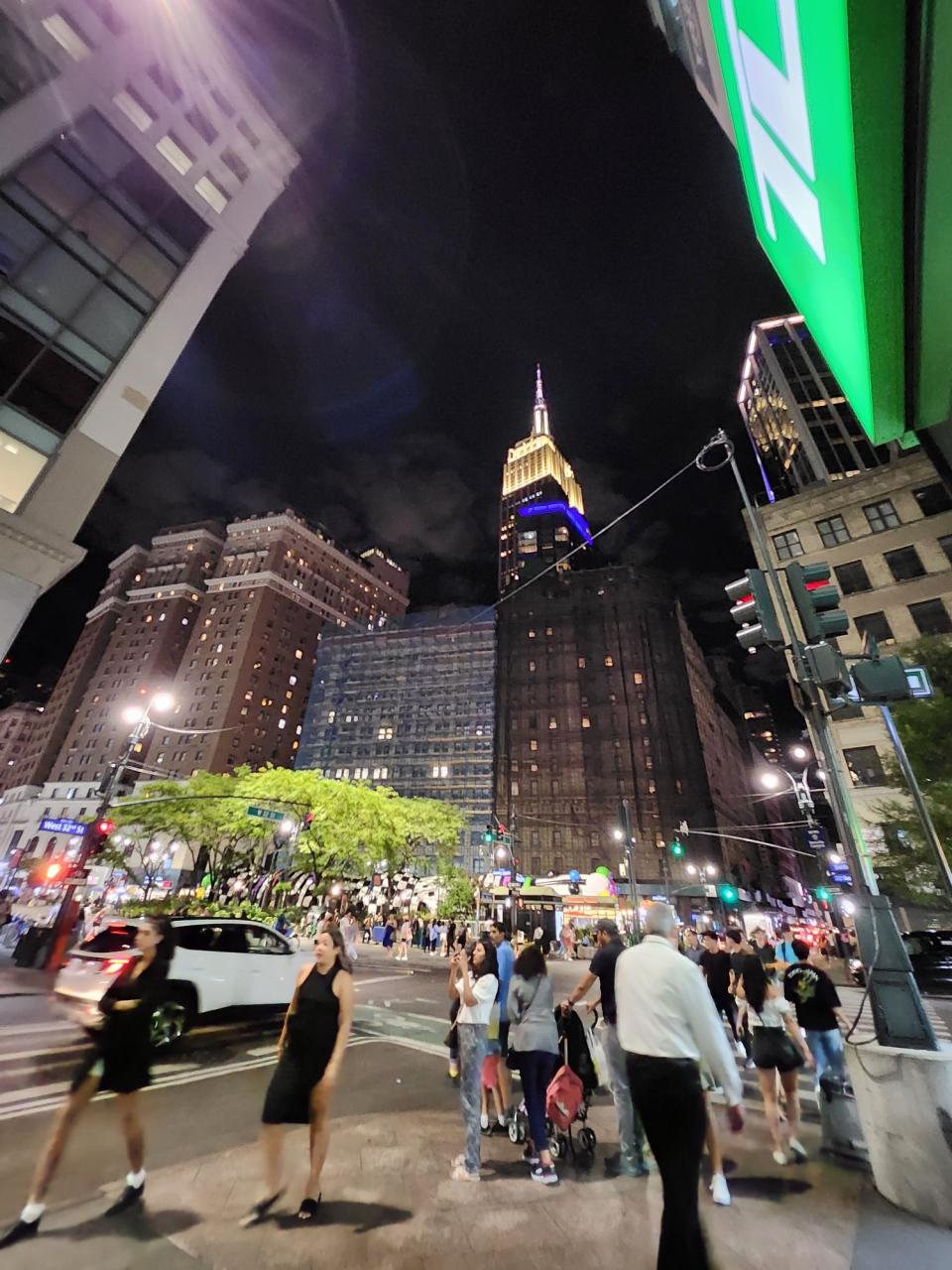 <p>A picture taken with the Galaxy Z Flip 4 showing a wider angle of the Empire State Building at night shot from a nearby street. A pedestrian crossing is also in the frame, along with more surrounding buildings.</p>
