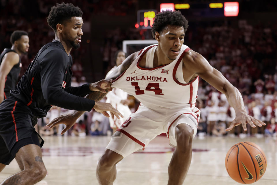 Oklahoma forward Jalon Moore (14) has his uniform grabbed by Houston guard Mylik Wilson during the second half of an NCAA college basketball game Saturday, March 2, 2024, in Norman, Okla. (AP Photo/Garett Fisbeck)