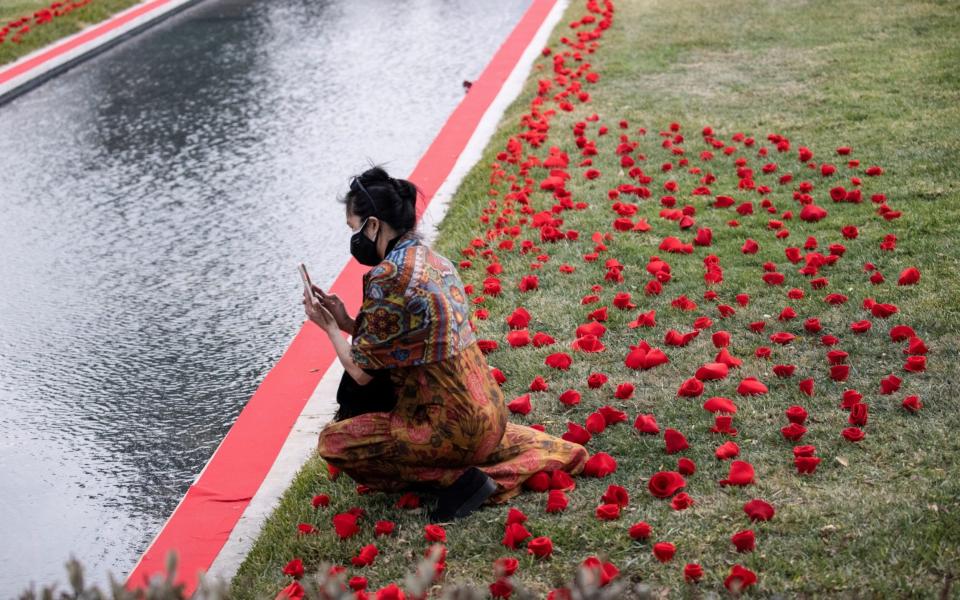 A person uses her mobile phone by a tribute to the victims of the COVID-19 pandemic by the Reflecting Pool at the Hollywood Forever Cemetery - Mario Anzuoni/Reuters