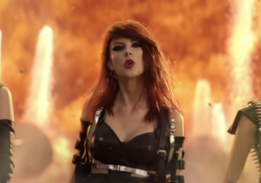 Woman in a black outfit with a fiery explosion behind her