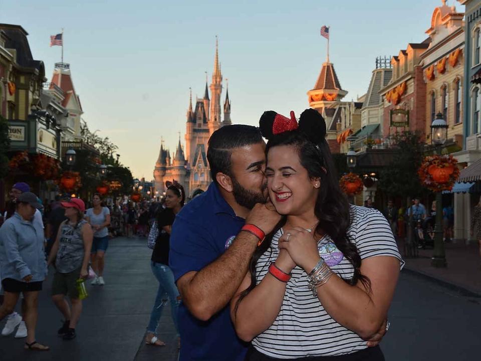 stephanie and her husband posing on main street at magic kingdom