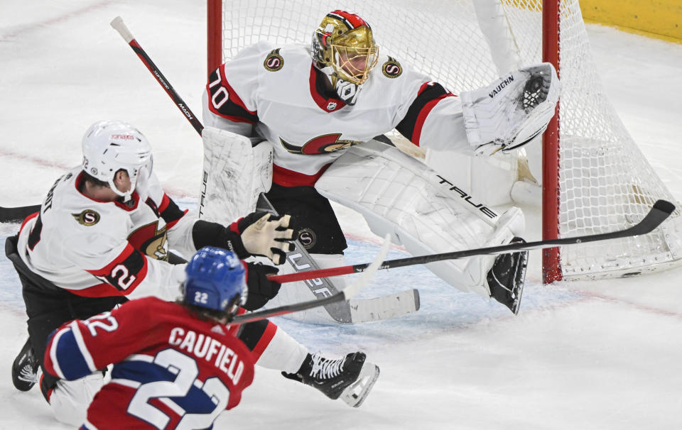 Ottawa Senators goaltender Joonas Korpisalo makes a glove save on Montreal Canadiens' Cole Caufield (22) as Senators' Thomas Chabot (72) tries to block the shot during the second period of an NHL hockey game in Montreal, Tuesday, Jan. 23, 2024. (Graham Hughes/The Canadian Press via AP)