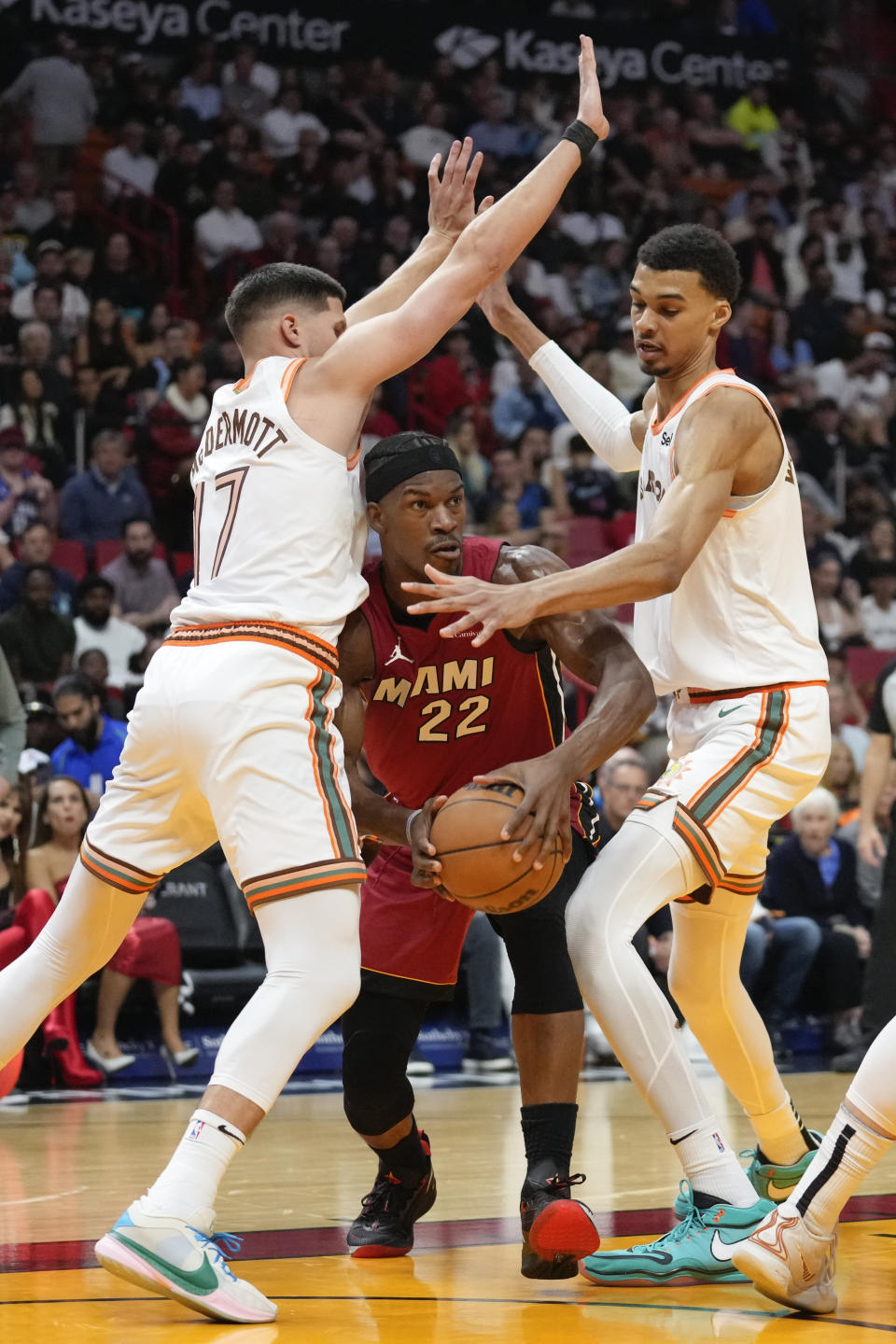 Miami Heat forward Jimmy Butler (22) comes under pressure from San Antonio Spurs forward Doug McDermott (17) and center Victor Wembanyama during the first half of an NBA basketball game, Wednesday, Feb. 7, 2024, in Miami. (AP Photo/Rebecca Blackwell)