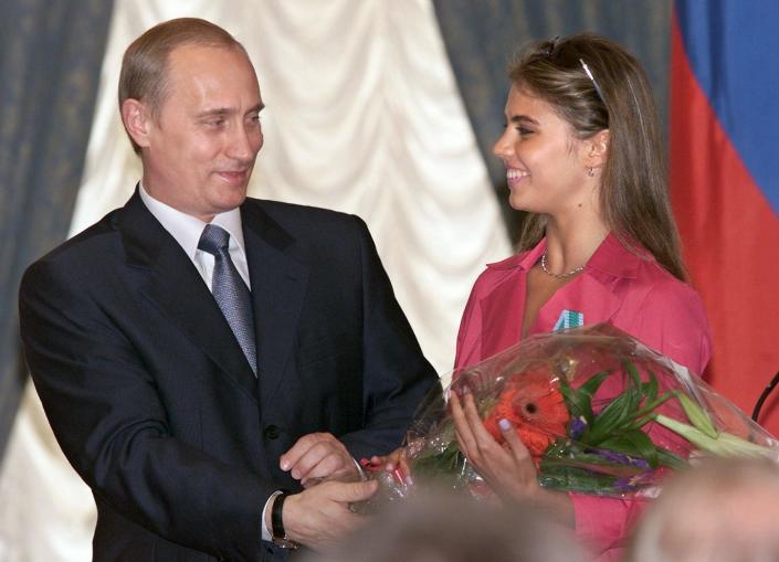 Russian President Vladimir Putin (L) hands flowers to Alina Kabayeva, Russian rythmic gymnastics star and Olympic prize winner, after awarding her with an Order of Friendship during annual award ceremony in the Kremlin 08 June 2001. (Sergei ChirikovAFP via Getty Images)