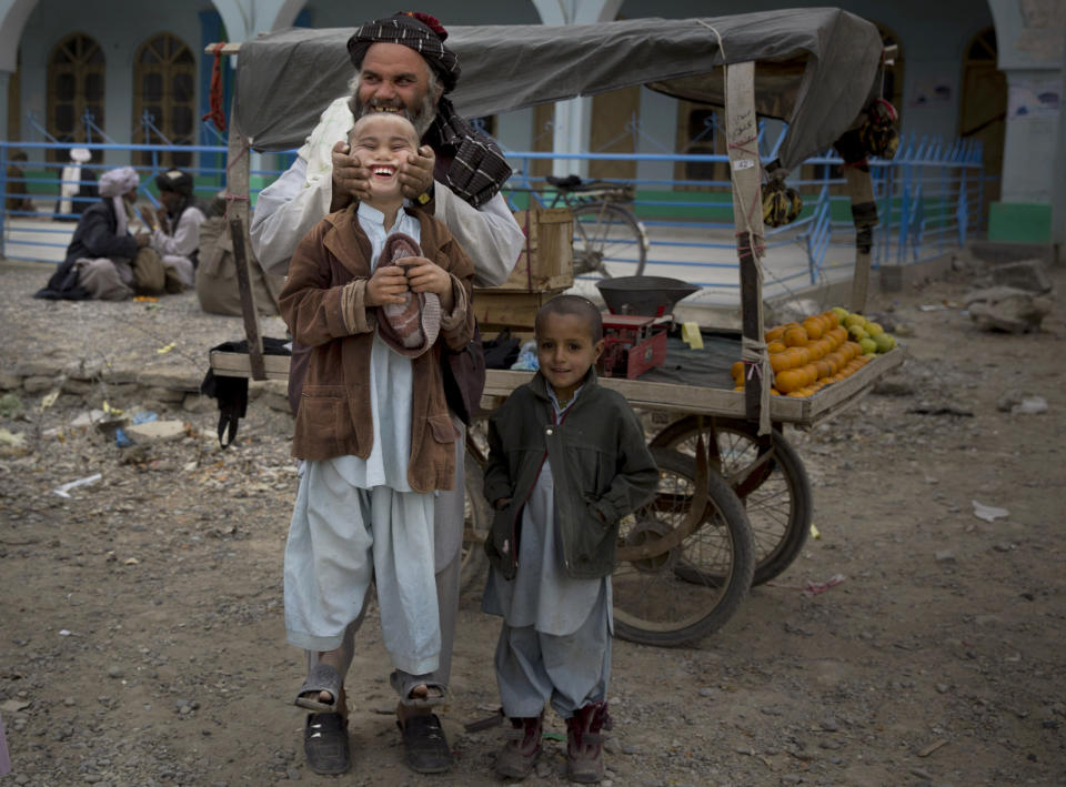 FILE - A fruit seller lifts his son by his cheeks in the center of Kandahar, Afghanistan, Wednesday, March 12, 2014. (AP Photo/Anja Niedringhaus, File)