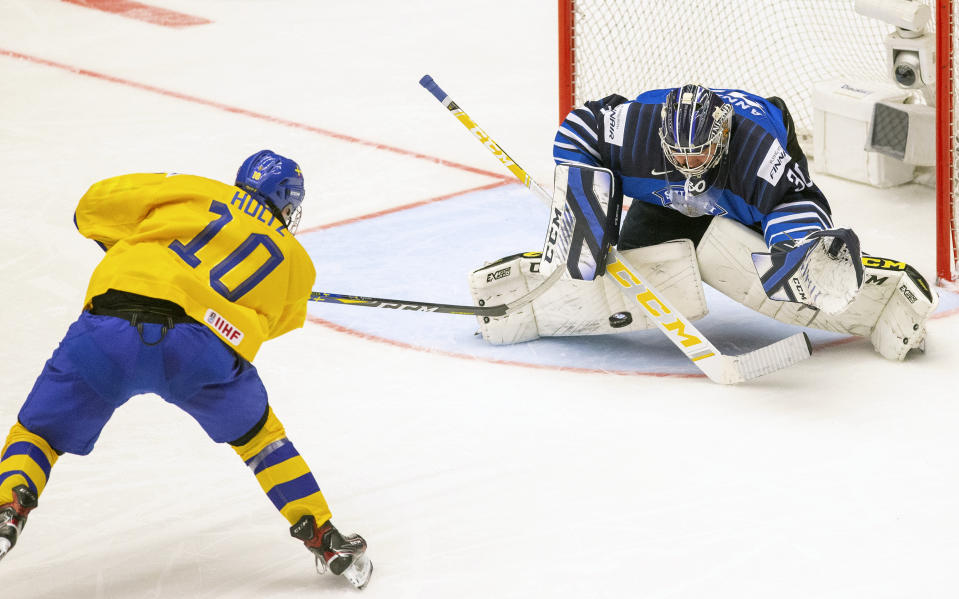 Alexander Holtz of Sweden, left, shoots against goalkeeper Justus Annunen of Finland during the World U20 Ice Hockey Championships Group A match between Sweden and Finland in Trinec, Czech Republic, Thursday Dec. 26, 2019. (Vladimir Prycek/CTK via AP)