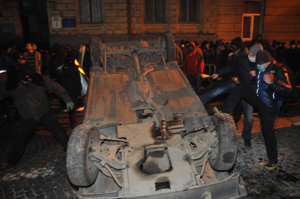 Ukrainian protesters turn over a police car outside police headquarters in Lviv, western Ukraine, early Wednesday, Feb. 19, 2014. The violence on Tuesday was the worst in nearly three months of anti-government protests that have paralyzed Ukraine's capital, Kiev, in a struggle over the identity of a nation divided in loyalties between Russia and the West, and the worst in the country's post-Soviet history. (AP Photo/ Pavlo Palamarchuk)