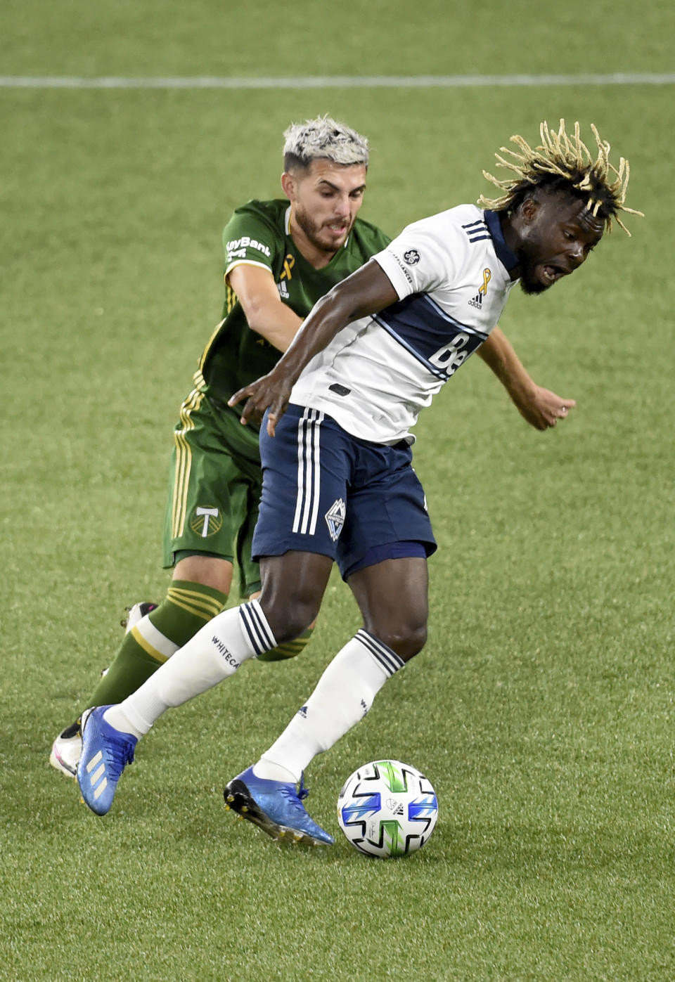 Portland Timbers midfielder Cristhian Paredes, left, battles for the ball with Vancouver Whitecaps midfielder Leonard Owusu during the first half of an MLS soccer match in Portland, Ore., Sunday, Sept. 27, 2020. (AP Photo/Steve Dykes)