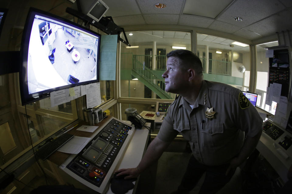 Sheriff Brian Martin looks at a video monitor in a control area of the Lake County Jail in Lakeport, Calif., on Tuesday, April 16, 2019. The sheriff instituted many reforms and changes, including a larger video surveillance monitor, following the 2015 suicide of a woman who had repeatedly cried for help. Her son's wrongful death suit resulted in a $2 million settlement. (AP Photo/Eric Risberg)