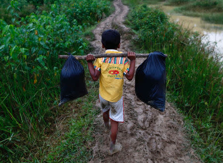 A Rohingya refugee boy carries his belongings as he walks to a makeshift camp in Cox's Bazar, Bangladesh September 18, 2017. REUTERS/Danish Siddiqui