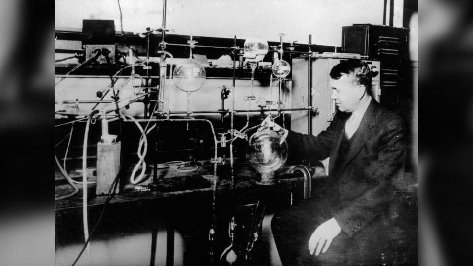 Prof. Harold Clayton Urey in a laboratory, surrounded by spherical glassware and tubes.