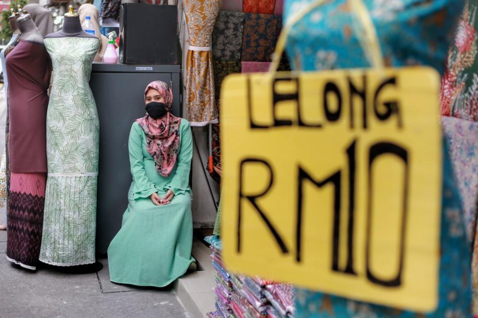 A worker waits for customers in front of a fabric store on Jalan Masjid India amid the conditional movement control order in Kuala Lumpur May 7, 2020. — Picture by Ahmad Zamzahuri