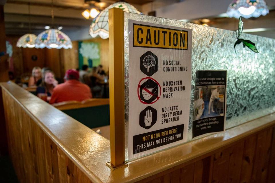 A sign inside the Apple Bistro in Placerville on Friday, July 24, 2020, discourages the use of “oxygen deprivation masks” and “latex dirty germ spreader” gloves. The owner of the restaurant has refused to close down indoor dining, acting against a July 13 California public health order requiring restaurants to temporarily stop indoor dining, as well as other measures to slow the spread of COVID-19 after a resurgence in many California counties, including El Dorado County where the Apple Bistro is located.