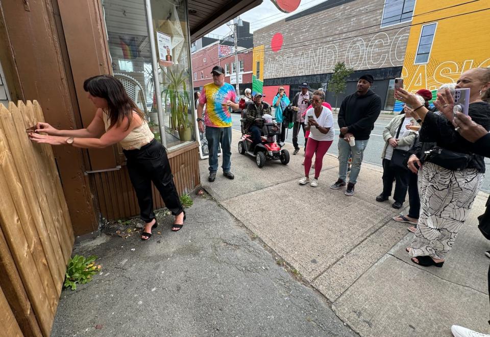 Michelle Strum, the owner of Alteregos Cafe in Halifax, placed a plaque in memory of three of her customers who have passed away on a wooden gate.