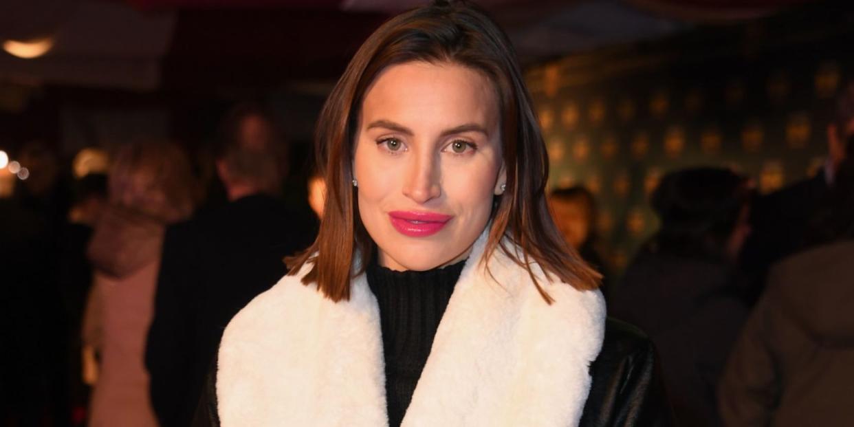 ferne mccann in january 2023 in a black coat with large white fluffy sleeves and collar