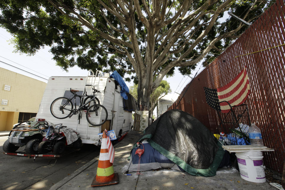 A RV vehicle is parked next to a tent on the streets in an industrial area of Los Angeles, Wednesday, July 31, 2019. (AP Photo/Damian Dovarganes)