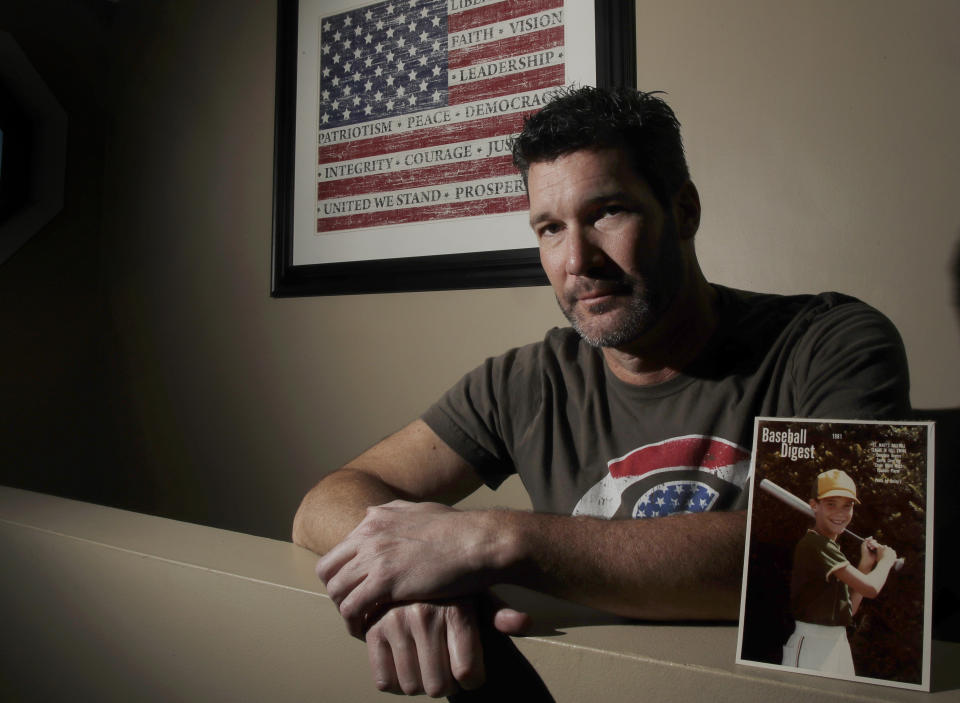 In this Dec. 18, 2019 photo, Joey Covino poses for a photo at his home in Saugus, Mass., with a photo of himself as a 9-year-old boy. | Elise Amendola—AP