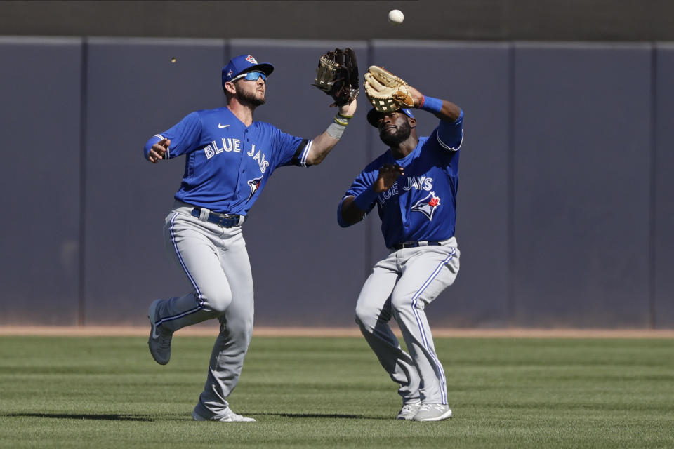 Toronto Blue Jays' Forest Wall, left, catches a ball hit by New York Yankees' Erik Kratz for an out while avoiding teammate Anthony Alford, right, during the fifth inning of a spring training baseball game Saturday, Feb. 22, 2020, in Tampa. (AP Photo/Frank Franklin II)