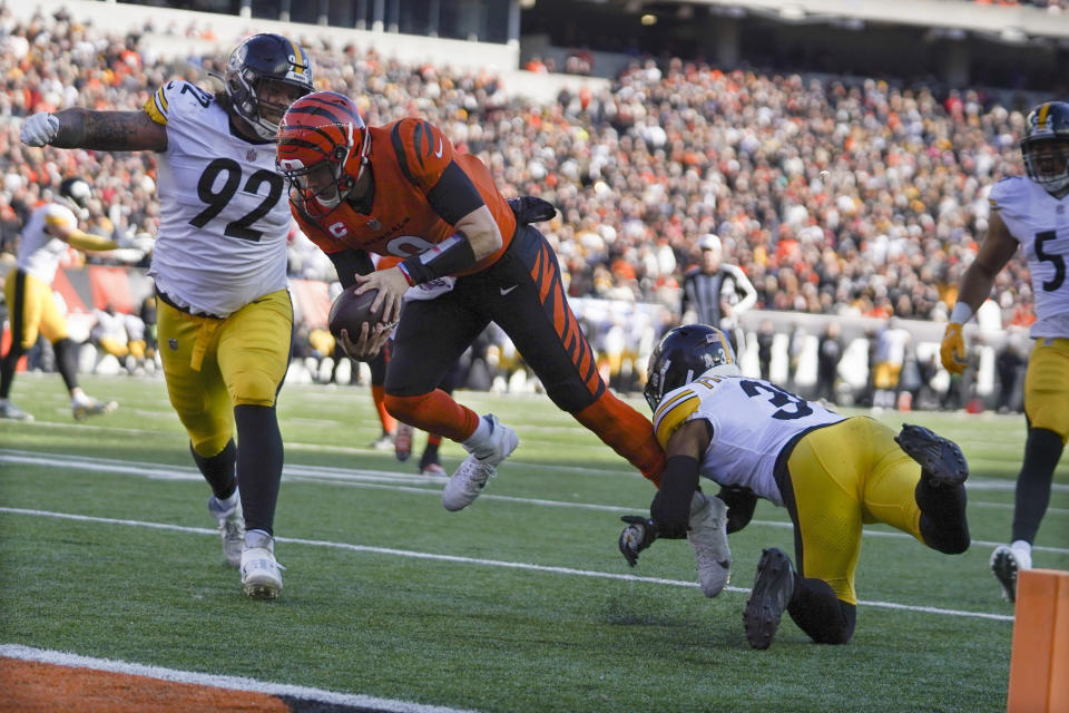 Cincinnati Bengals quarterback Joe Burrow (9) runs between Pittsburgh Steelers free safety Minkah Fitzpatrick (39) and defensive end Isaiahh Loudermilk (92) as he scrambles his way to a touchdown in the first half of an NFL football game, Sunday, Nov. 28, 2021, in Cincinnati. (AP Photo/Jeff Dean)