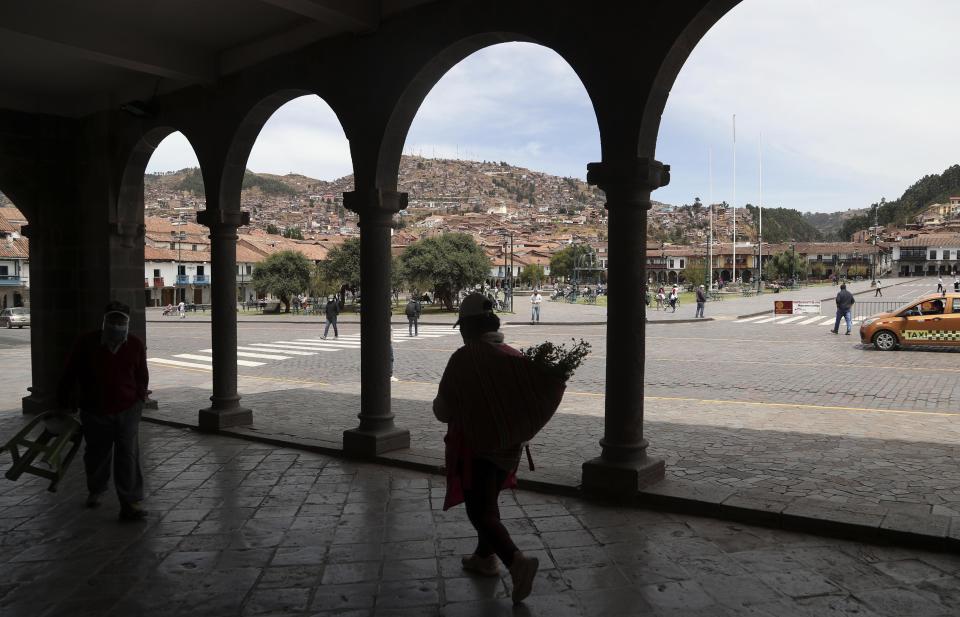 A woman carries herbs in the Plaza de Armas in downtown Cusco, Peru, Thursday, Oct. 29, 2020. All major sites around Cusco are currently open for free, in hopes of sparking any tourism after the COVID-19 pandemic brought it to a standstill. (AP Photo/Martin Mejia)