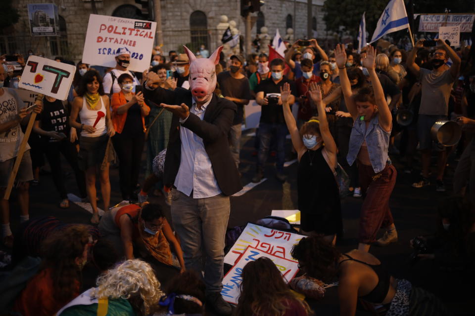 Protesters, defying orders to maintain social distancing requirements, chant slogans outside of the Prime Minister's residence in Jerusalem, Tuesday, July 14, 2020. Thousands of Israelis demonstrated outside the official residence of Benjamin Netanyahu, calling on the embattled Israeli leader to resign as he faces a trial on corruption charges and grapples with a deepening coronavirus crisis. (AP Photo/Ariel Schalit)