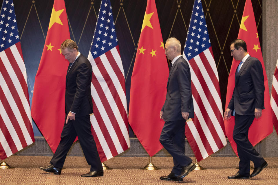U.S. Trade Representative Robert Lighthizer, left, points at markers on the floor as he leads Chinese Vice Premier Liu, center, and Treasury Secretary Steven Mnuchin, right, to their position for a family photo at the Xijiao Conference Center in Shanghai on Wednesday, July 31, 2019. (AP Photo/Ng Han Guan, Pool)