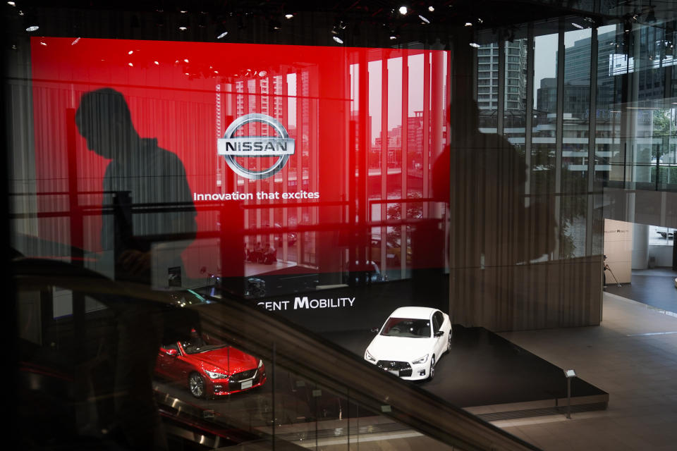 FILE - In this July 25, 2019, file photo, a man rides an escalator as Nissan vehicles are showcased in the Nissan Gallery in Yokohama, west of Tokyo. Nissan, reeling from a scandal over its former superstar executive Carlos Ghosn, sank into red ink in the latest quarter as its vehicle sales fell around the world, and the Japanese automaker slashed its profit forecast for the year. (AP Photo/Jae C. Hong, File)