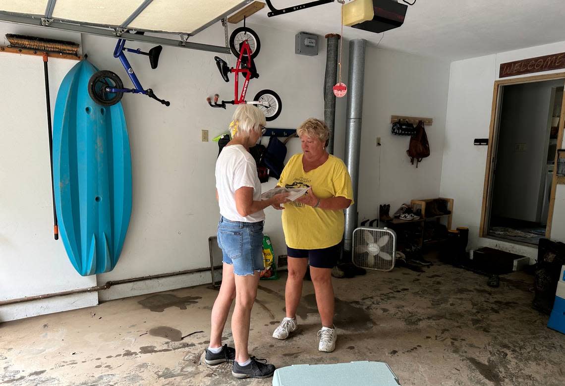 Kathy Bujnak accepts a gift on behalf of the family from neighbor, Sue Hickey. Hickey brought them frozen banana oat bran muffins and offered the family her support after flooding damaged their home.