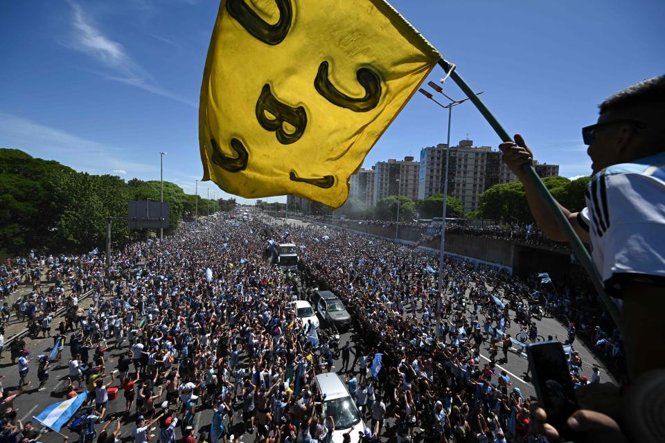 Argentina's players celebrate on board a bus with supporters after winning the Qatar 2022 World Cup tournament as they tour through Buenos Aires' downtown on December 20, 2022. - Millions of ecstatic fans are expected to cheer on their heroes as Argentina's World Cup winners led by captain Lionel Messi began their open-top bus parade of the capital Buenos Aires on Tuesday following their sensational victory over France. (Photo by Luis ROBAYO / AFP) (Photo by LUIS ROBAYO/AFP via Getty Images)