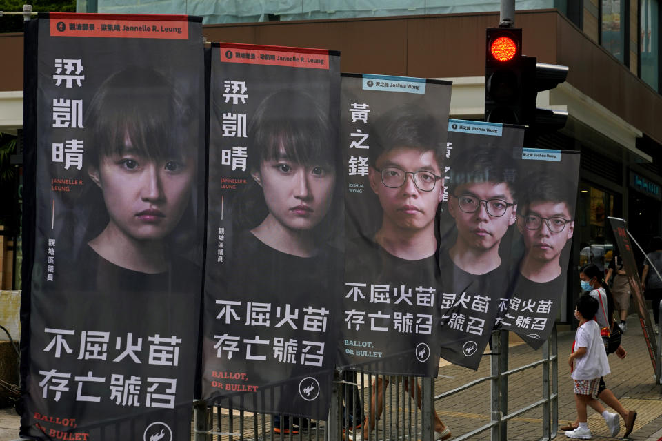 Banners of a pro-democracy candidate Joshua Wong, wearing glasses, are displayed outside a subway station in Hong Kong Saturday, July 11, 2020, in an unofficial "primary" for pro-democracy candidates ahead of legislative elections. At least 12 pro-democracy nominees including Wong have had their nominations disqualified for an upcoming legislative election in September, after they were deemed to not comply with the requirement to uphold the city's Basic Law and pledge allegiance to Hong Kong and Beijing. (AP Photo/Kin Cheung)