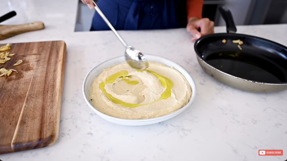 Someone adding oil to their hummus