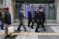 A man looks at a stock quotation board as passers-by walk past, outside a brokerage in Tokyo December 4, 2013. REUTERS/Toru Hanai