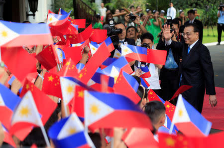 Chinese Premier Li Keqiang gestures to the students while waving Chinese and Philippine flags during his official visit at the Malacanang presidential palace in Manila, Philippines November 15, 2017. REUTERS/Romeo Ranoco