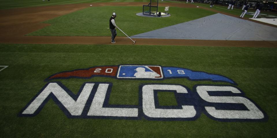 A worker gets the field ready for Game 1 of the National League Championship Series baseball game between the Milwaukee Brewers and the Los Angeles Dodgers Friday, Oct. 12, 2018, in Milwaukee. (AP Photo/Charlie Riedel)