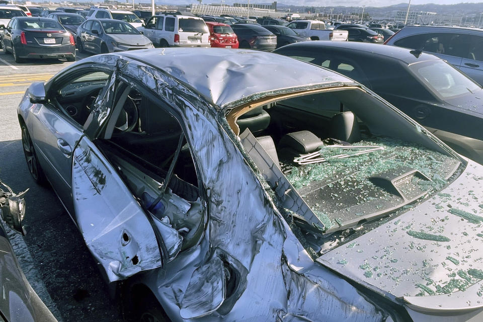 A damaged car is seen in an on-airport employee parking lot after tire debris from a Boeing 777 landed on it at San Francisco International Airport, Thursday, March 7, 2024. A United Airlines jetliner bound for Japan made a safe landing in Los Angeles on Thursday after losing a tire while taking off from San Francisco. (AP Photo/Haven Daley)