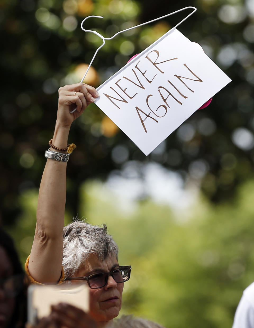 Mindy Brown, of Yazoo City, Miss. holds up a sign and a hanger at the Capitol in Jackson, Miss., voicing her opposition to state legislatures passing abortion bans that prohibit most abortions once a fetal heartbeat can be detected, Tuesday, May 21, 2019. In addition, there are no provisions for rape or incest. Mississippi is among the states that have passed and signed into law such legislation. (AP Photo/Rogelio V. Solis)