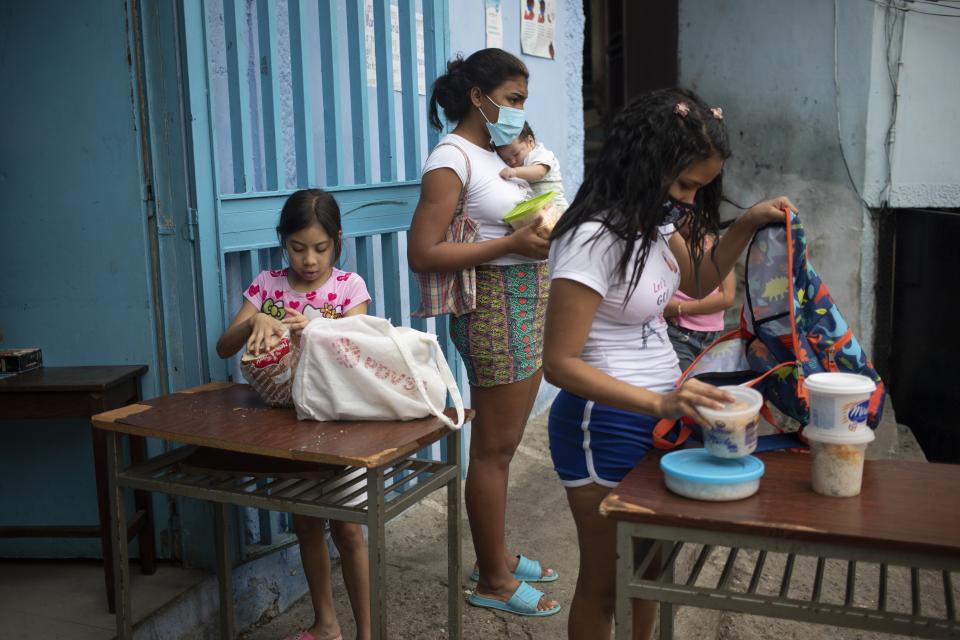 Children put donated food into their backpacks at the San Antonio de Padua soup kitchen in the Petare neighborhood of Caracas, Venezuela, Thursday, June 10, 2021, amid the new coronavirus pandemic. (AP Photo/Ariana Cubillos)