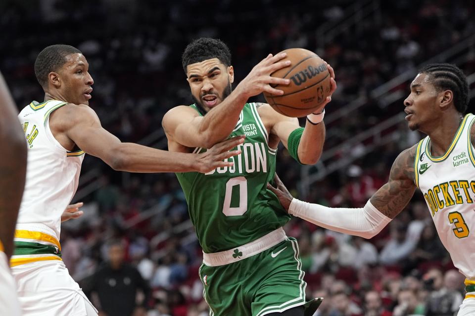 Boston Celtics' Jayson Tatum (0) drives to the basket as Houston Rockets' Kevin Porter Jr. (3) an d Jabari Smith Jr. defend during the first half of an NBA basketball game Monday, March 13, 2023, in Houston. (AP Photo/David J. Phillip)