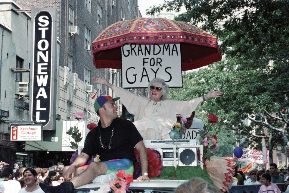 FILE - E.G. Smith, left, and his mother, Norma Isaacs, 88, sitting under an umbrella with a sign that reads, "Grandma For Gays," ride past the site of the original Stonewall Inn in New York's Greenwich Village during the annual Gay and Lesbian Pride Parade, June 25, 1989. The start of June marks the beginning of Pride month around the U.S. and some parts of the world, celebrating the lives and experiences of LGBTQ+ communities as well as raising awareness about ongoing struggles and pushing back against efforts to roll back civil rights gains that have been made. (AP Photo/Sergio Florez, File)