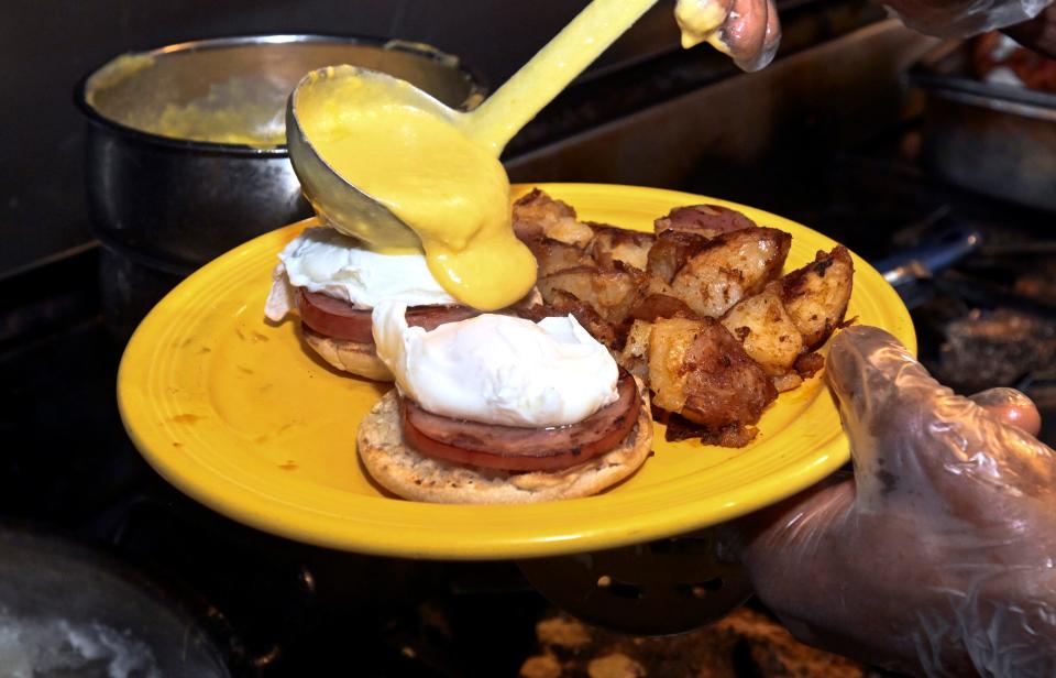 Homemade hollandaise sauce is poured on Eggs Benedict in the kitchen at the Fig Tree Cafe.
