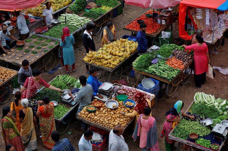 FILE PHOTO: Customers buy fruit and vegetables at an open air evening market in Ahmedabad, India