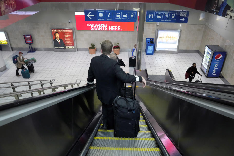 FILE - A pilot rides an escalator down to the baggage claim area inside the Southwest Airlines terminal at St. Louis Lambert International Airport, Dec. 28, 2022, in St. Louis. With its flights now running on a roughly normal schedule, Southwest Airlines is turning its attention to luring back customers and repairing damage to a reputation for service after canceling 15,000 flights around Christmas. The disruptions started with a winter storm and snowballed when Southwest's ancient crew-scheduling technology failed. (AP Photo/Jeff Roberson, File)