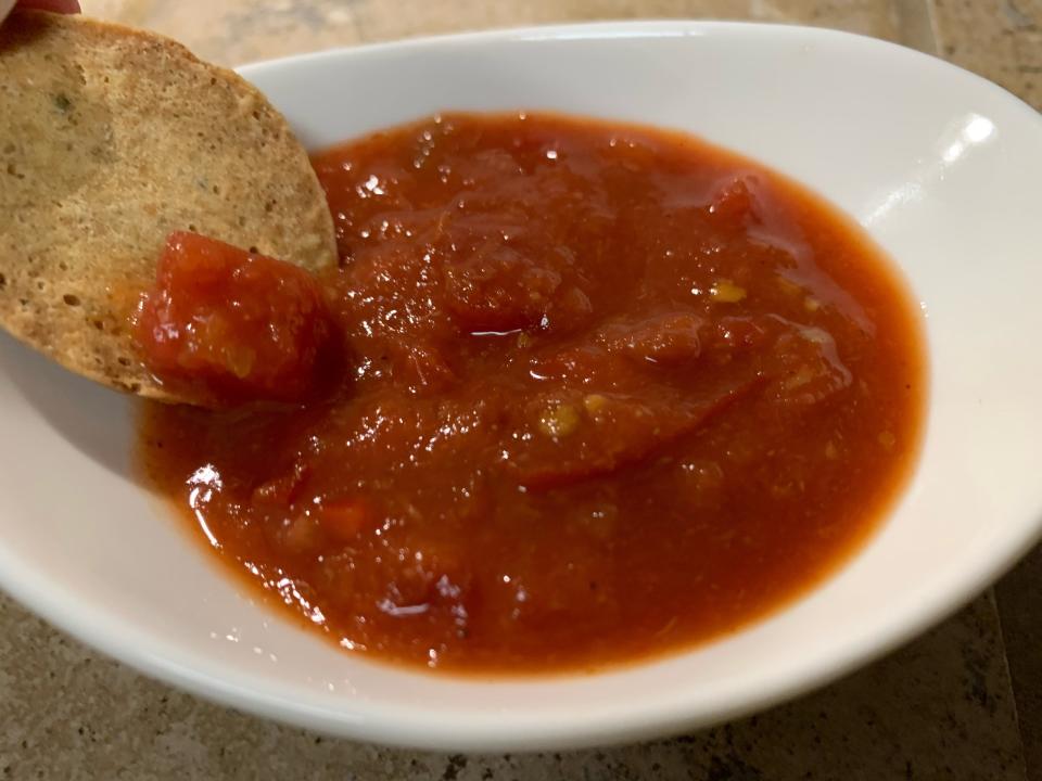 a chip being dipped in Trader Joe's bloody mary salsa, which is in a small white bowl