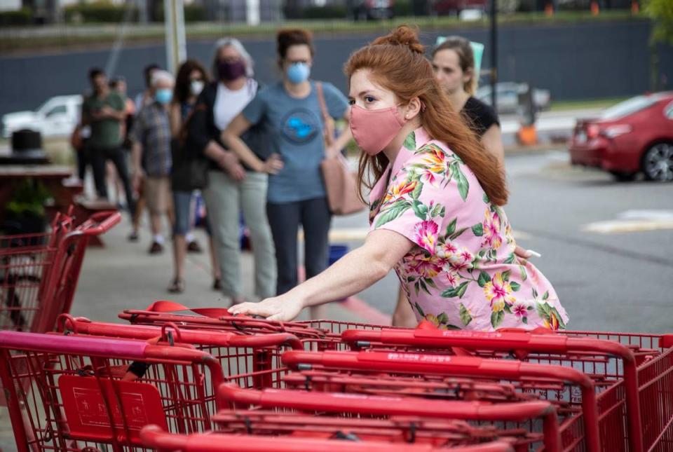 Grocery worker Jody Alexander positions and sanitizes carts at Trader Joe’s in Raleigh Tuesday, April 7, 2020. The store is limiting 40 customers in the store at once as customers are asked to adhere to social distancing standards while waiting in lines.