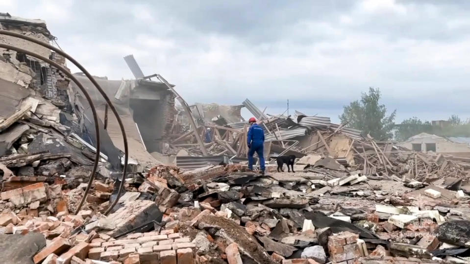 In this photo released by Russian Emergency Ministry Press Service on Wednesday, Aug. 9, 2023, An emergency Ministry employee and his dog work at the side of the Zagorsk Optical and Mechanical Plant after the blast in the city of Sergiev Posad, Moscow Region, about 65 km (41miles) north-east of Moscow, Russia. An explosion Wednesday, on the grounds of a factory north of Moscow that makes optical equipment for Russia's security forces wounded dozens people, six of them severely, officials said. (Russian Emergency Ministry Press Service via AP)