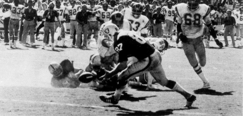 FILE - In this Sept. 11, 1978, file photo, on the final play of the game between the Oakland Raiders and the San Diego Chargers, Raiders' Dave Casper (87) scoops up the ball fumbled by Raider's quarterback Ken Stabler on the five-yard line, in San Diego. Stabler dropped back to pass and was pressured by Chargers linebacker Woodrow Lowe. With nowhere to throw the ball, Stabler either fumbled or pushed the ball forward on purpose, depending on which side of the rivalry is telling the story. Teammate Pete Banaszak then knocked the ball further ahead from about the 13-yard line as it rolled toward the end zone. Tight end Dave Casper kicked the ball forward at the 5 and then fell on it in the end zone with no time remaining. (Thane McIntosh/The San Diego Union-Tribune via AP, File)
