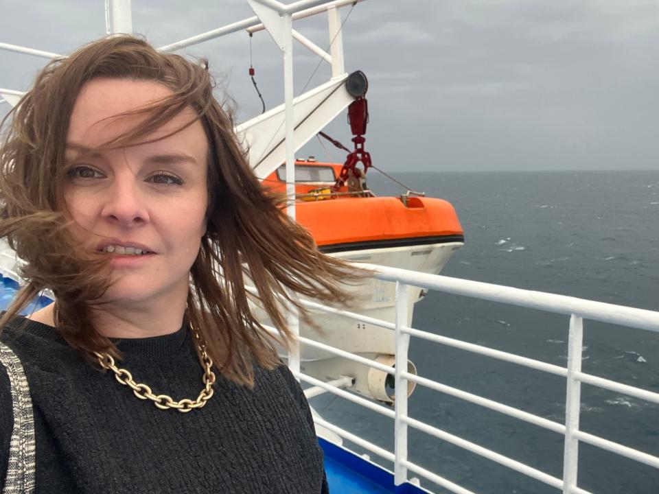 katie standing on the deck of a ferry in greece with wind blowing her hair across her face